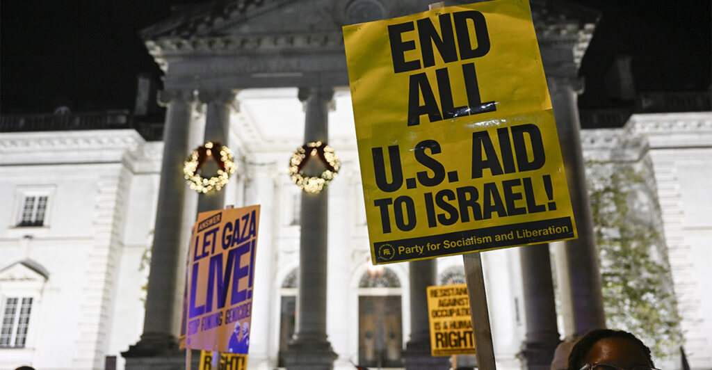 Pro-Palestinian demonstrators hold up signs saying "End all US aid to Israel" and other slogans during National Christmas tree lighting in Washington, D.C.