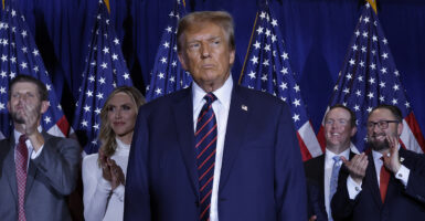 Donald Trump looks intently in a blue suit with an American flag pin.