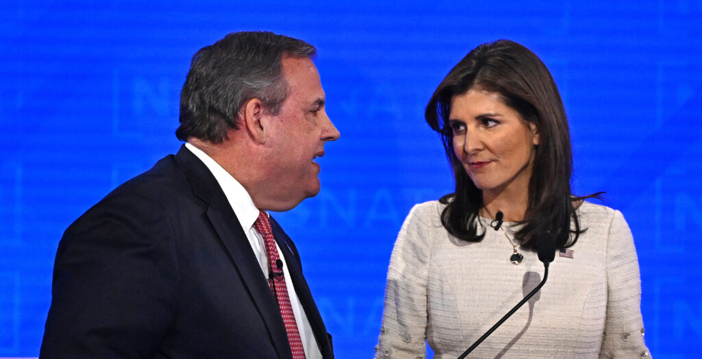 Chris Christie in a suit speaks with Nikki Haley in a cream dress
