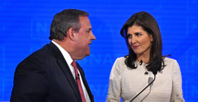 Chris Christie in a suit speaks with Nikki Haley in a cream dress