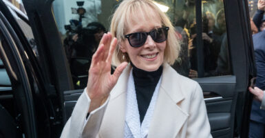 E. Jean Carroll waves in a suit and dark sunglasses