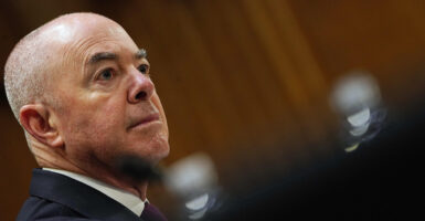 DHS Secretary Alejandro Mayorkas is seen seated in a dark suit during a hearing.