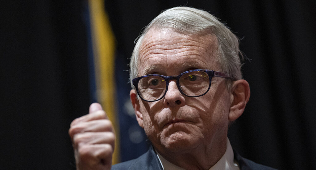 Ohio Gov. Mike DeWine purses his lips in a suit while wearing glasses