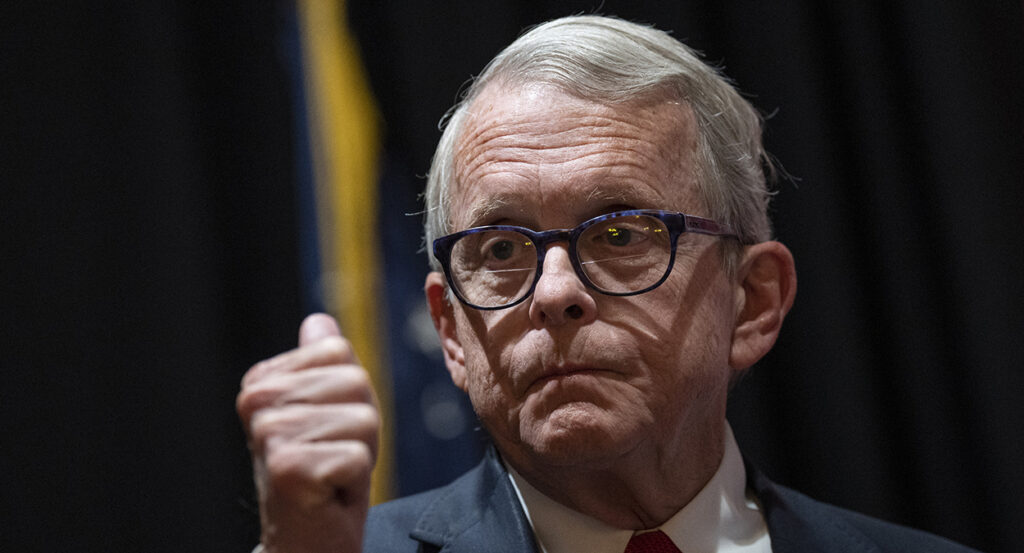 Ohio Gov. Mike DeWine makes a thumbs up gesture in a suit