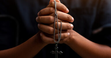A black person prays with a crucifix