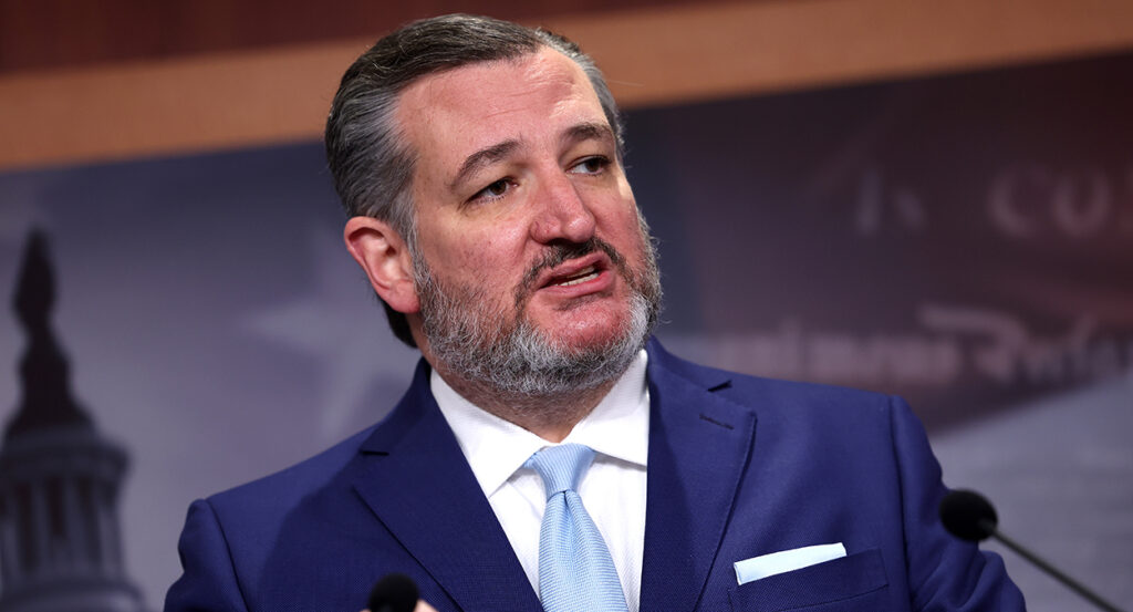 Ted Cruz speaks in a blue suit with a blue tie and wearing a salt-and-pepper beard