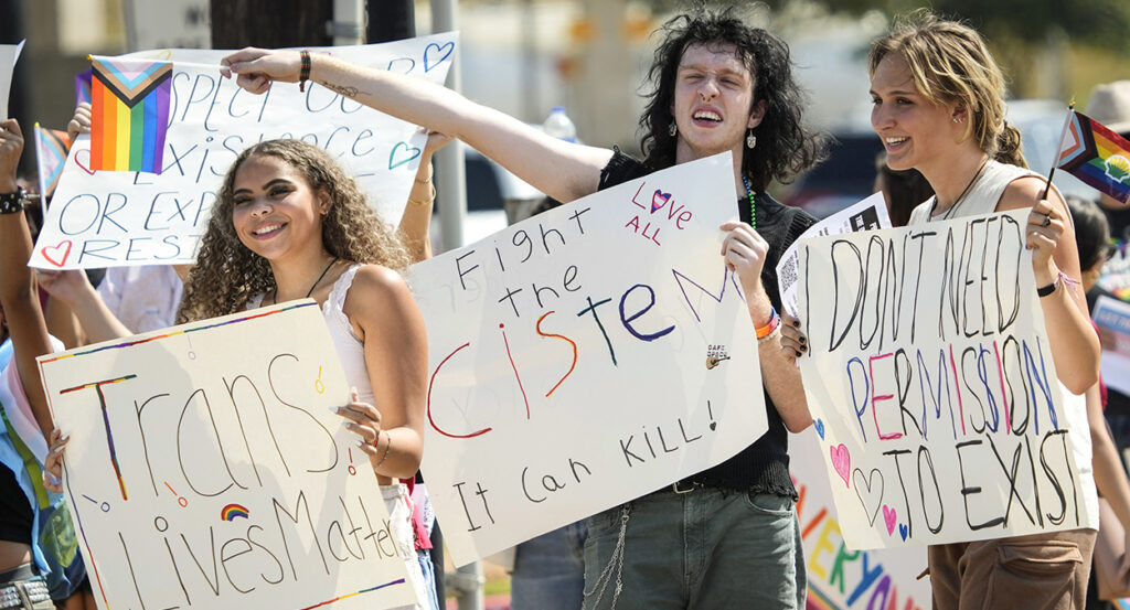 Young protesters hold transgender signs