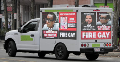 A truck with a digital billboard with a "Fire Gay" message and Claudine Gay’s picture drives through Harvard Square.
