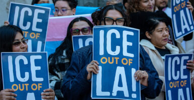Activists pushing Los Angeles to become a sanctuary city, holding signs saying “ICE out of LA”