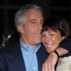 Jeffrey Epstein in a blue suit coat hugs Ghislaine Maxwell