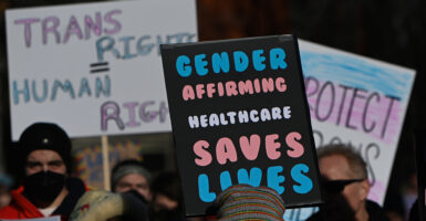 Protesters march with signs reading "Trans Rights Are Human Rights" and "Gender Affirming Healthcare Saves Lives"
