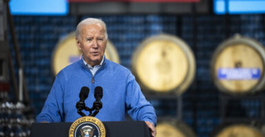 President Joe Biden stands behind a podium wearing a bright blue jacket.