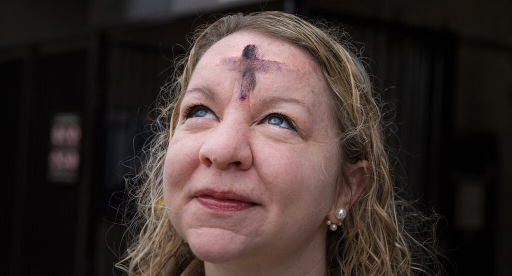 Woman looks at the sky wearing glitter ashes on her forehead for Ash Wednesday