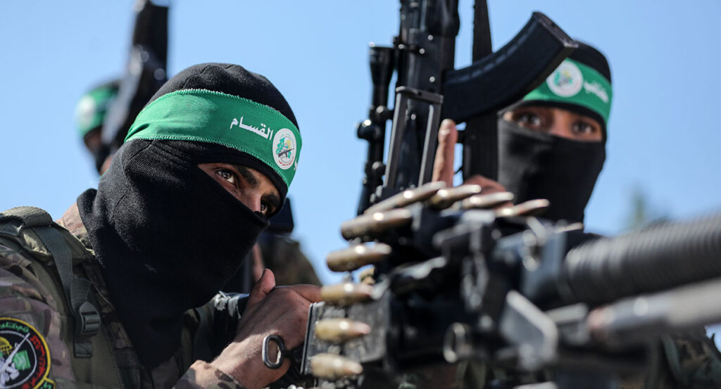 Two Hamas fighters in military regalia fire a machine gun