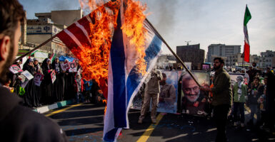 People burn the American and Israel flag in the streets of Iran.