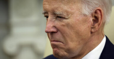 Joe Biden looks down with a grimace in a black suit