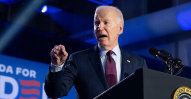 President Joe Biden angrily gestures in a blue suit with an American flag pin