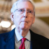 Minority Leader Mitch McConnell looks ahead in a dark blue suit and red tie.