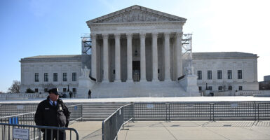 A police officer is seen standing outside the Supreme Court in a sunny day.