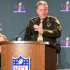 Sheriff McMahill stands at a podium with the NFL logo on it.. Behind him are panels with the Super Bowl LVIII logo on it.