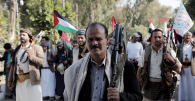 Houthis rebels hold guns and Palestinian flags.