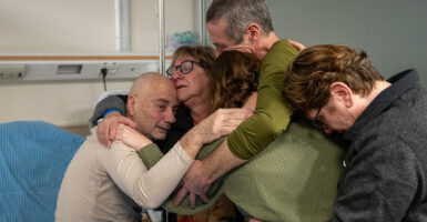 Five people hug each other in a hospital.