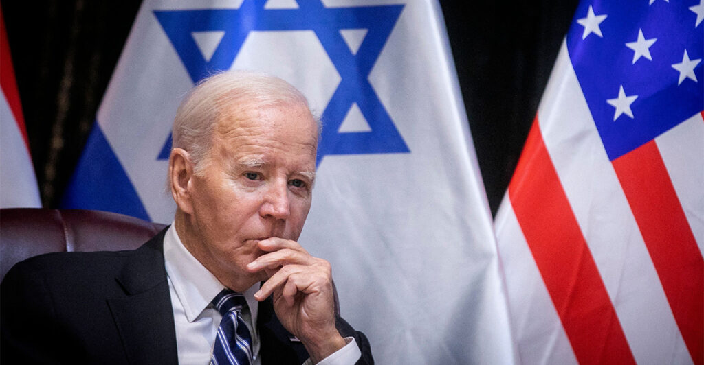 President Joe Biden sitting in front of The Israeli and American flags