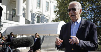 President Biden in a suit jacket with no tie talking to reporters outside the White House