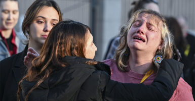 A woman is weeping and hugged by another outside at a protest