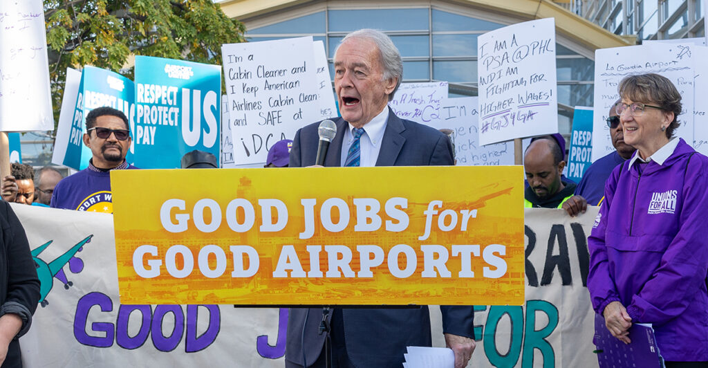 Senator Ed Markey speaking at a rally in front of a sign that says good jobs for good airports.