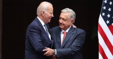 President Biden hugs Mexican President Lopez Obrador. Both men in suits.