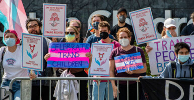Protesters wearing face masks hold signs reading "Celebrate trans children," and "trans kids belong."