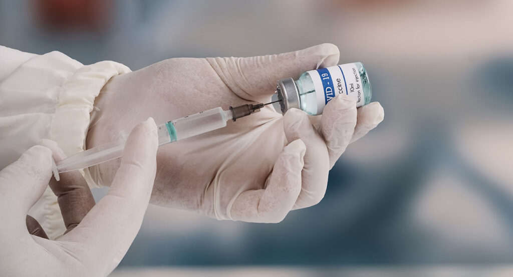 A doctor uses a syringe to prepare a COVID-19 vaccine.