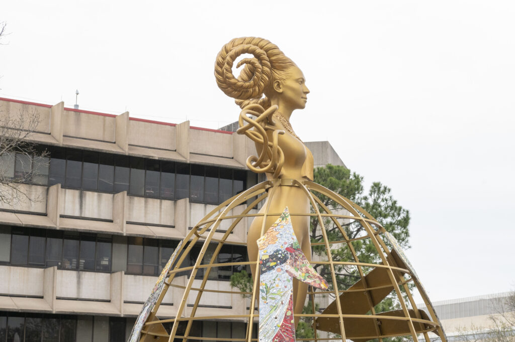 A golden, female-looking statue with braided horns overlooks the University of Houston campus.