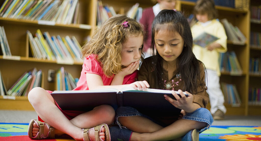 Two girls read book in children's library