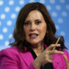 Gretchen Whitmer in a pink blazer gestures with a pencil in her right hand