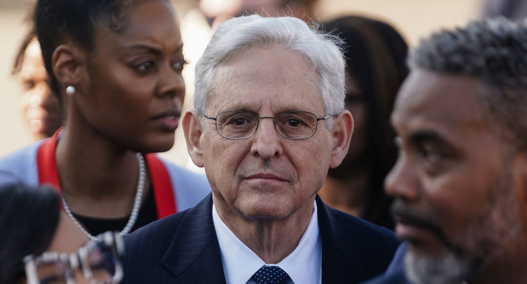 Merrick Garland looks ahead in a pin-stripe suit with a tie.