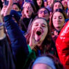 Young female rallygoers in France smile and shout to celebrate abortion enshrined in the constitution