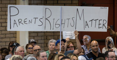 Parents at a protest holding up a large "Parents' Rights Matter" banner