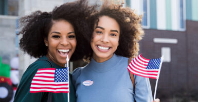 Black women wave small flags and smile after having voted