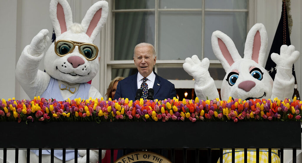 Joe Bien speaks in a suit with bunnies on his right and left