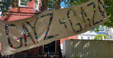 A banner made from cloth and sparkly stones reading 