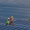 Two maintenance people in a field of solar panels