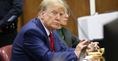 President Donald Trump sitting at a table in court with one of its attorneys