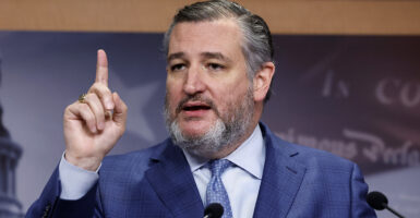Ted Cruz raises his finger in a blue suit