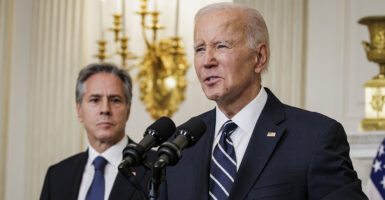 President Joe Biden at a podium delivering remarks with Secretary of State Antony Blinkin in the background