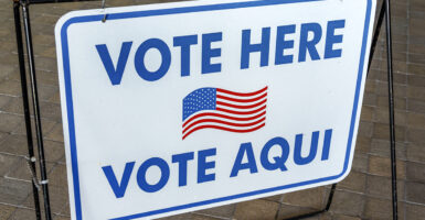 Sign With an American flag symbol that says "vote here" in both English and Spanish