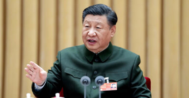 Chinese President Xi Jinping Sits at a microphone in a green military uniform, delivering remarks