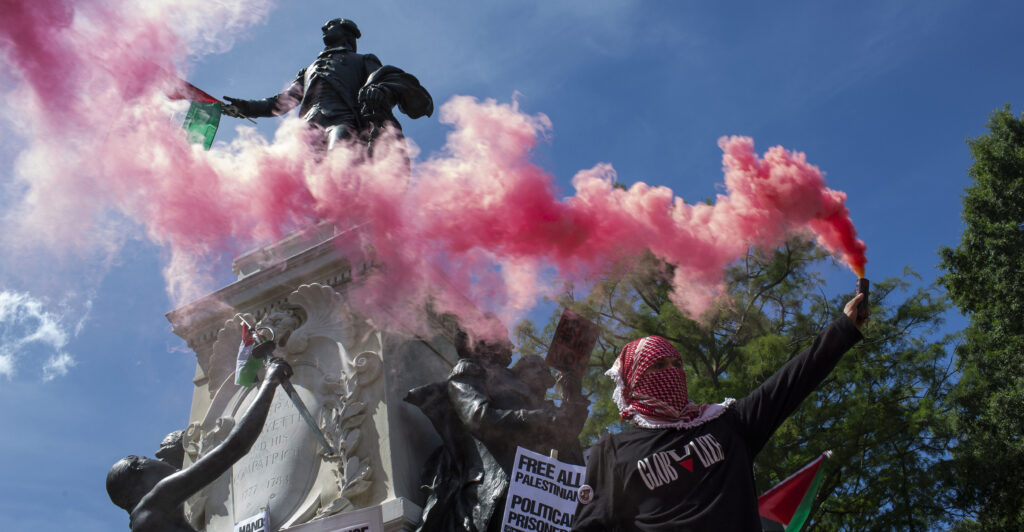 red smoke and graffiti surround a statue in Washington DC