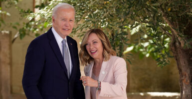 Joe Biden standing with Italian Prime Minister Giorgia Meloni near a tree